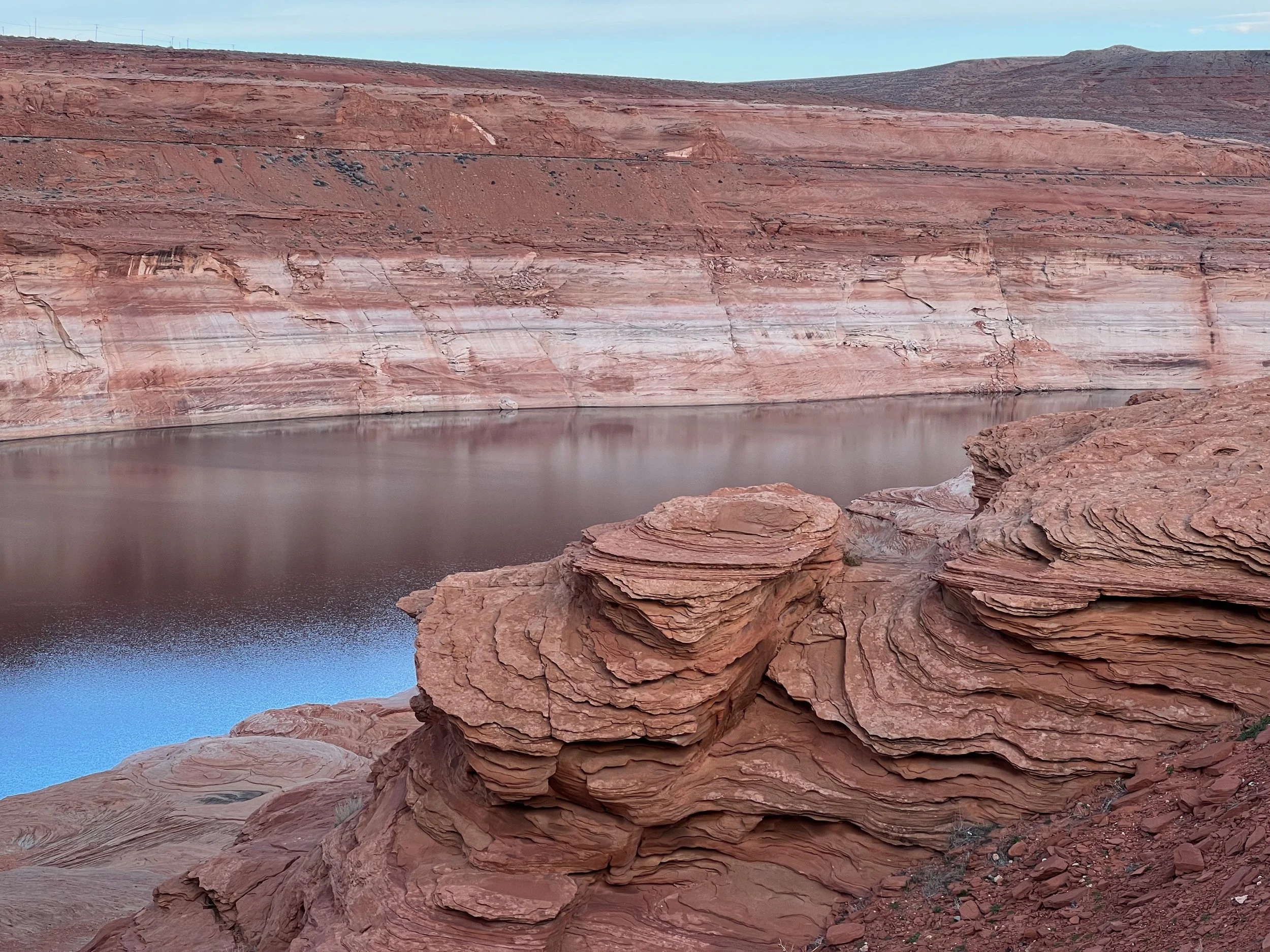 Red rock formations and a calm water body in a desert landscape