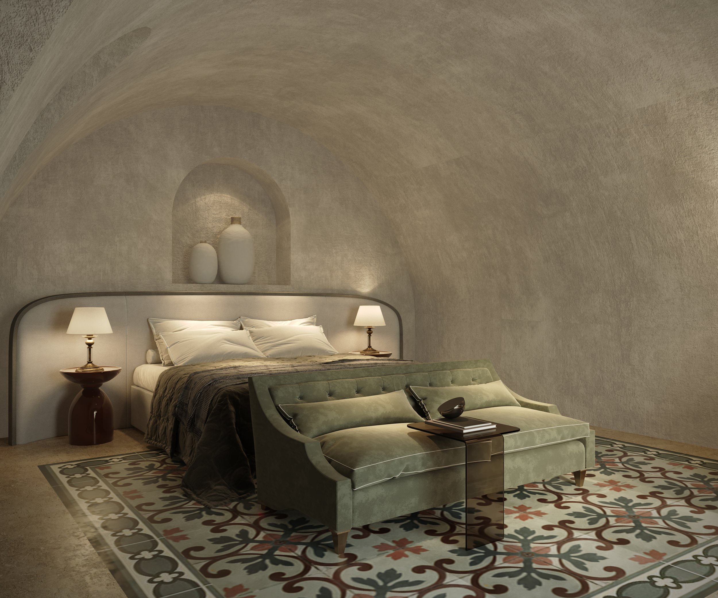 A cozy bedroom with a vaulted ceiling, modern bed with white bedding, two nightstands with lamps, a green velvet sofa at the foot of the bed, and decorative vases on a built-in niche above the headboard. The room features patterned floor tiles and neutral-toned walls.