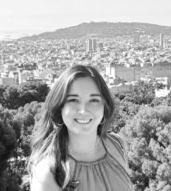 A woman taking a selfie outdoors near a rocky stream in a mountainous area.