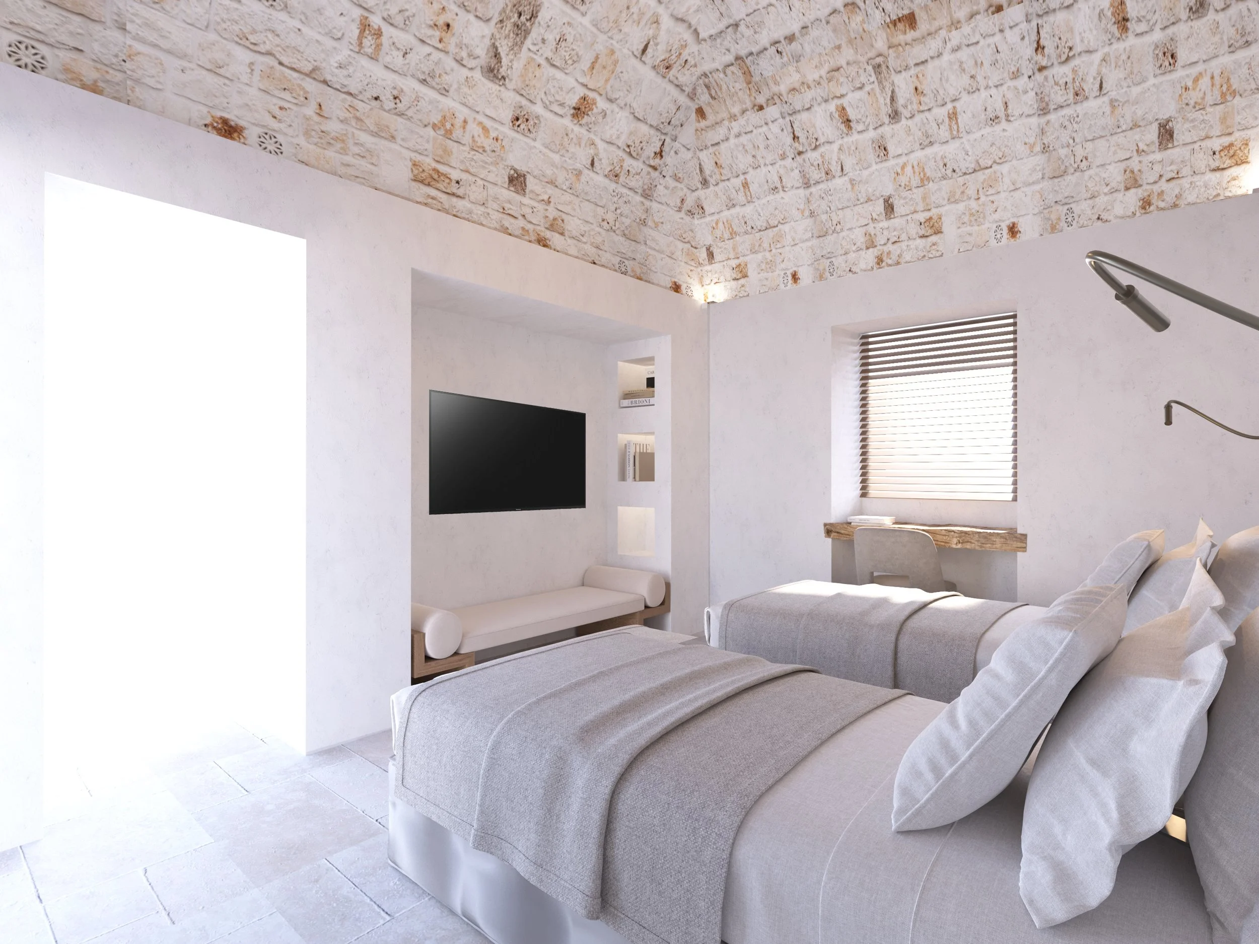 Modern bedroom with two beds, stone ceiling, wall-mounted TV, window with blinds, and a small desk.