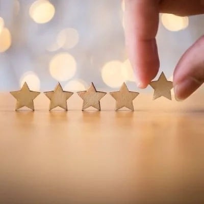 Hand placing a star-shaped object into a row of similar stars against a blurred festive background.