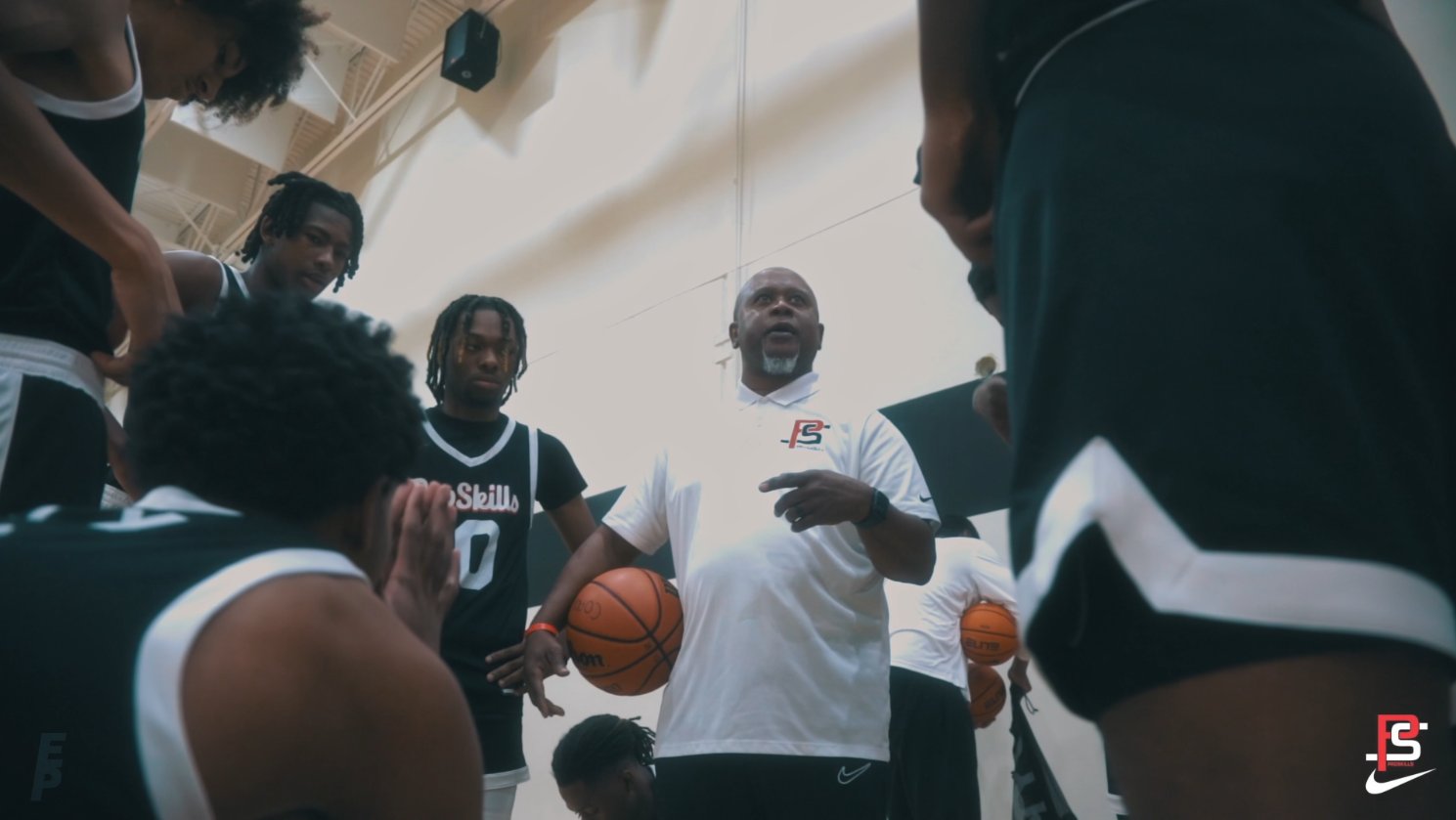 Screenshot from Alex Ervin Hype video for Nike Pro Skills AAU Basketball game.

Basketball coach giving instructions to a team during a timeout in a gymnasium, with players listening attentively.
