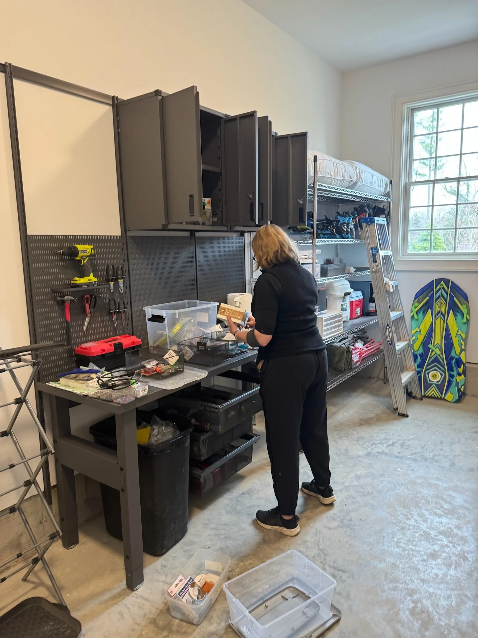 View of a garage with exercise bikes, storage shelves, cabinets, and various tools and equipment.