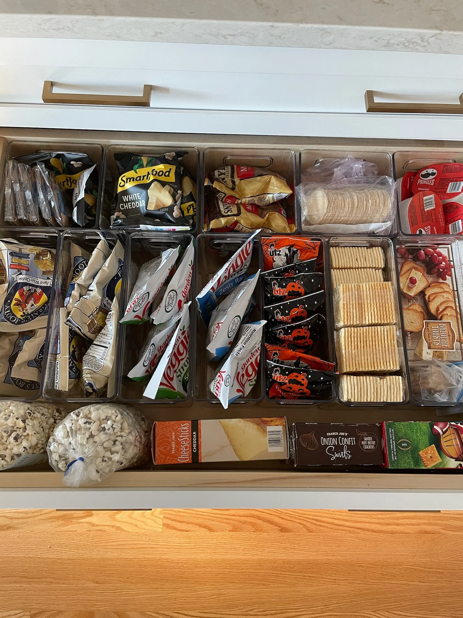 Organized snack drawer with various packaged snacks including crackers, chips, and popcorn.