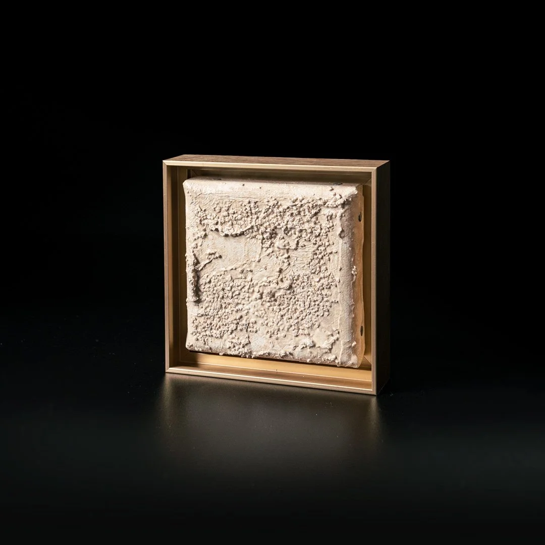 Artist: Veronika Vegesent. Title: One biophilic block.
Framed. 2023.
Materials: Plastic-free acrylic, sand from Helsinki, light Lemonite mineral pigment on linen canvas. Dimensions: 12 x 12 cm 4.7 x 4.7 in. 
Description: A one canvas piece out of a s