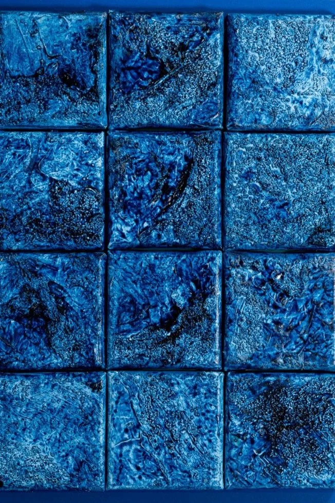 Close-up of nine blue textured square tiles with abstract patterns.