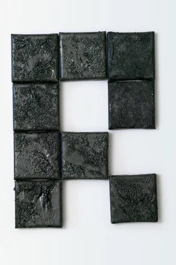 A collection of nine black tiles arranged to resemble the letter 'R' on a white background.