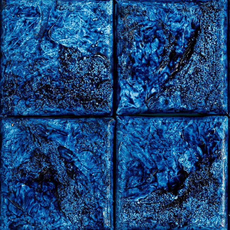 Close-up of textured blue tiles arranged in a 2x2 grid with intricate swirling and bubbling patterns.