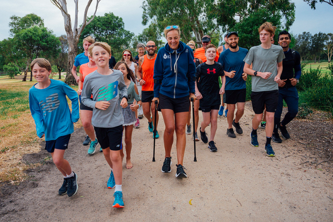 Group of people, including children and adults, participating in a community run in a park setting.