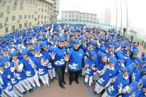 Large group of people wearing blue uniforms and caps, gathered outdoors.