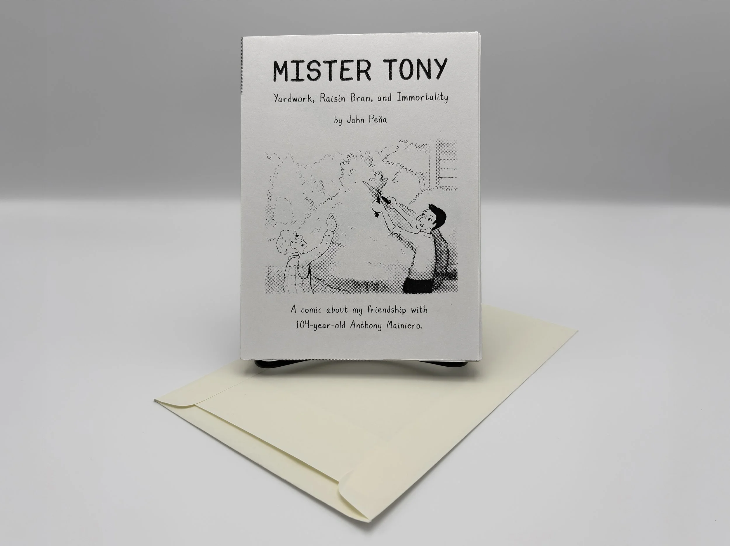 Front of Newsprint Book with screenprinted text resting on top of an archival envelope.