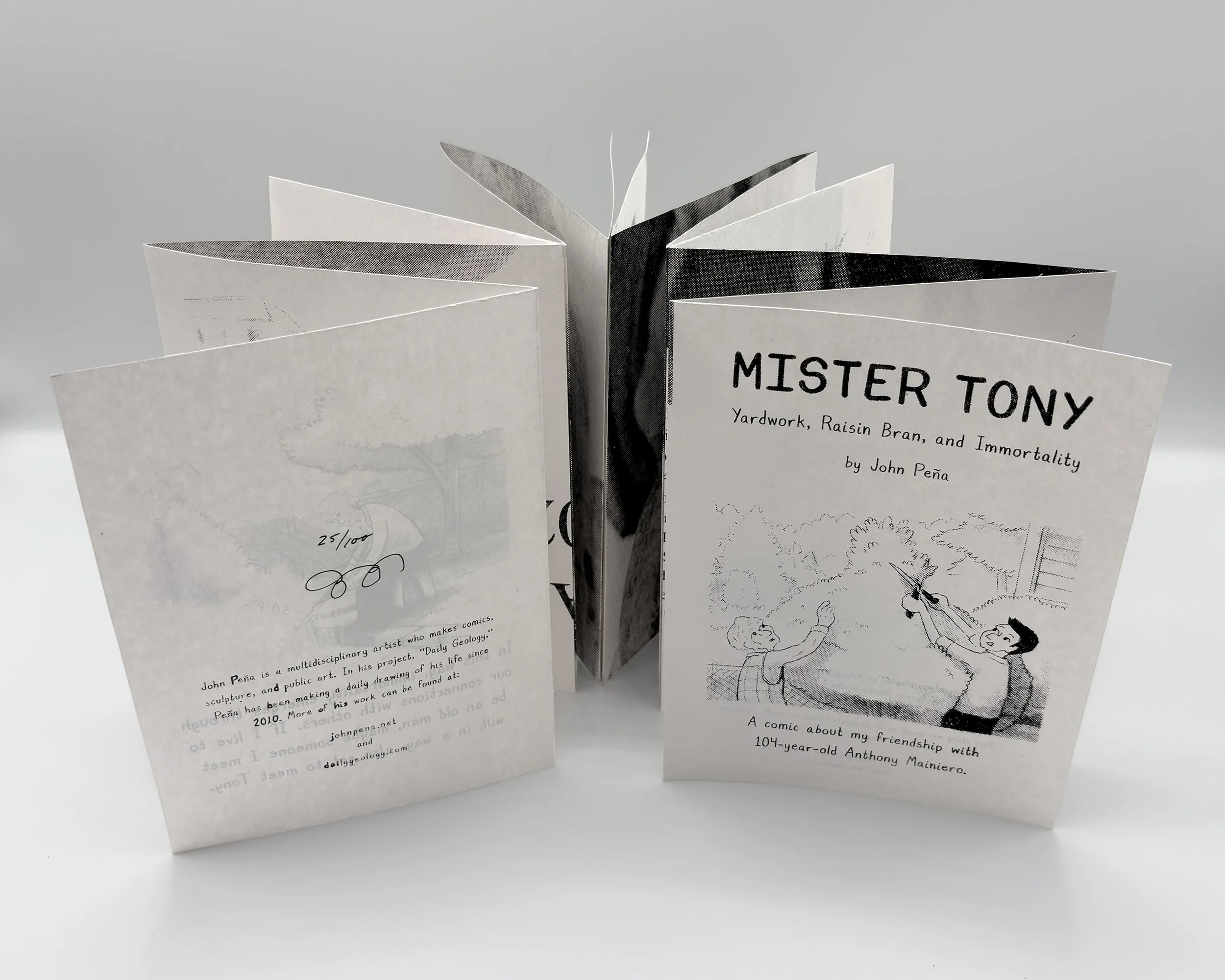 Newprinted books opened up to reveal complex interior black and white portrait.