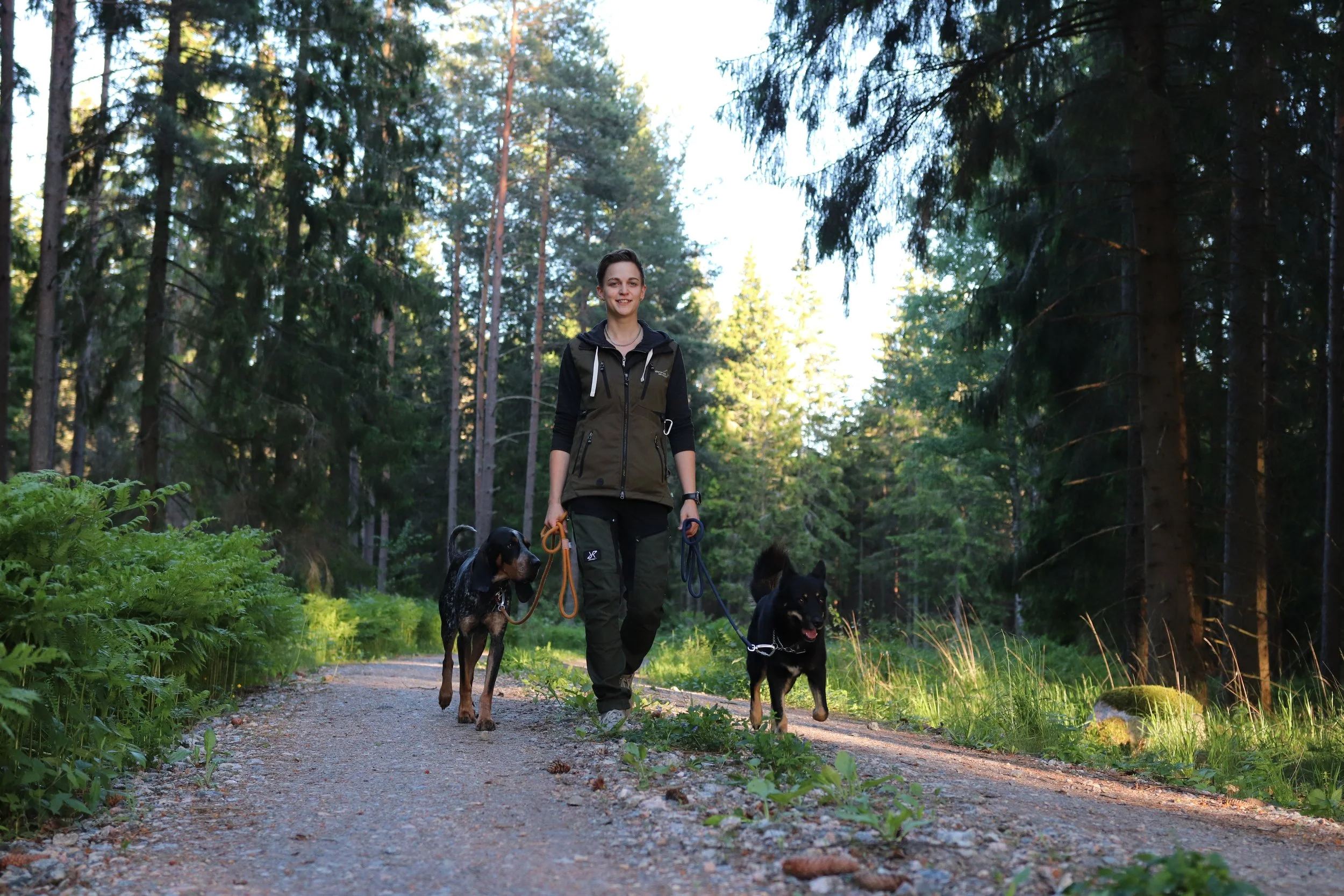 En tjej som promenerar avslappnat med två hundar.