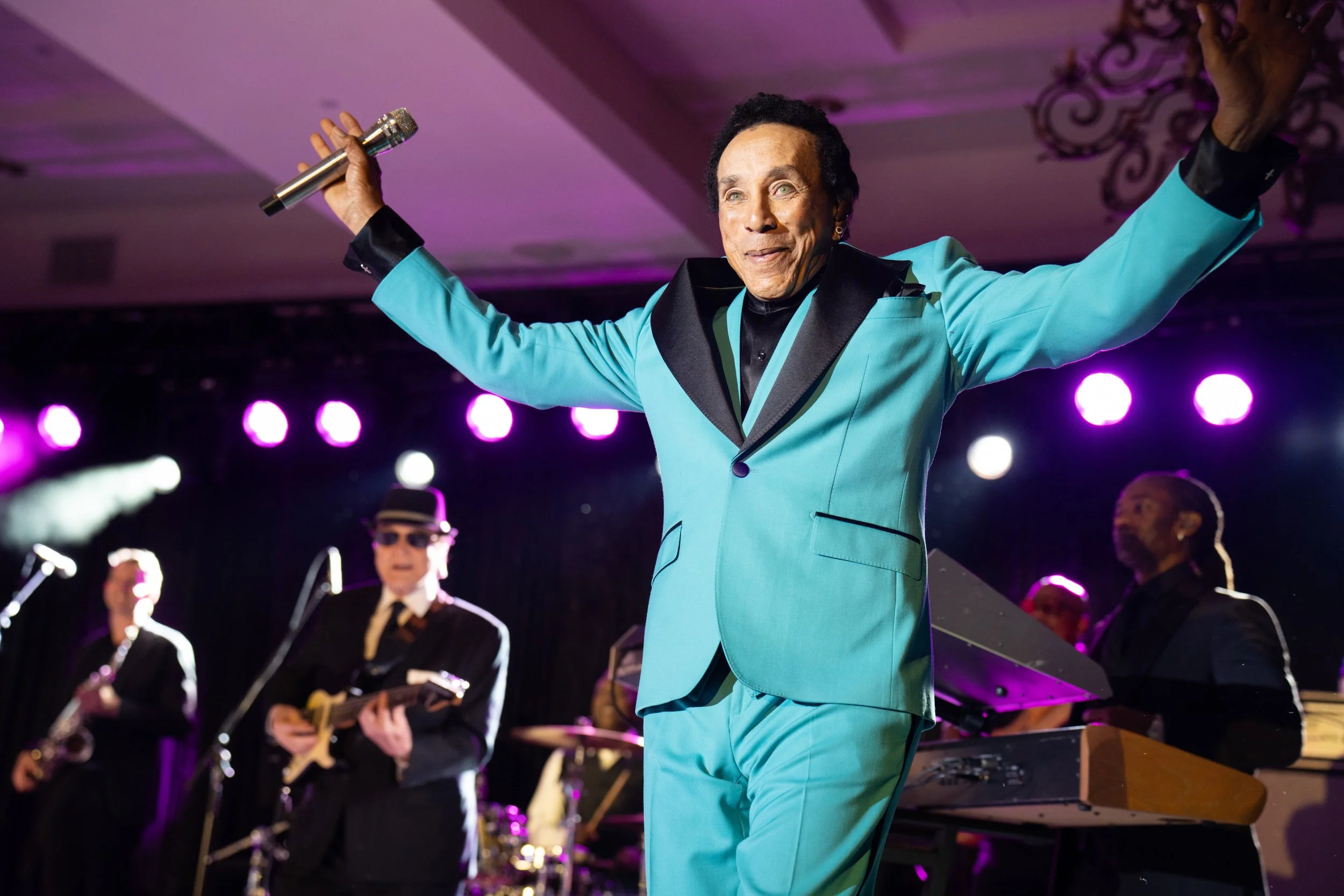 Headline performer on stage with arms raised at a private event