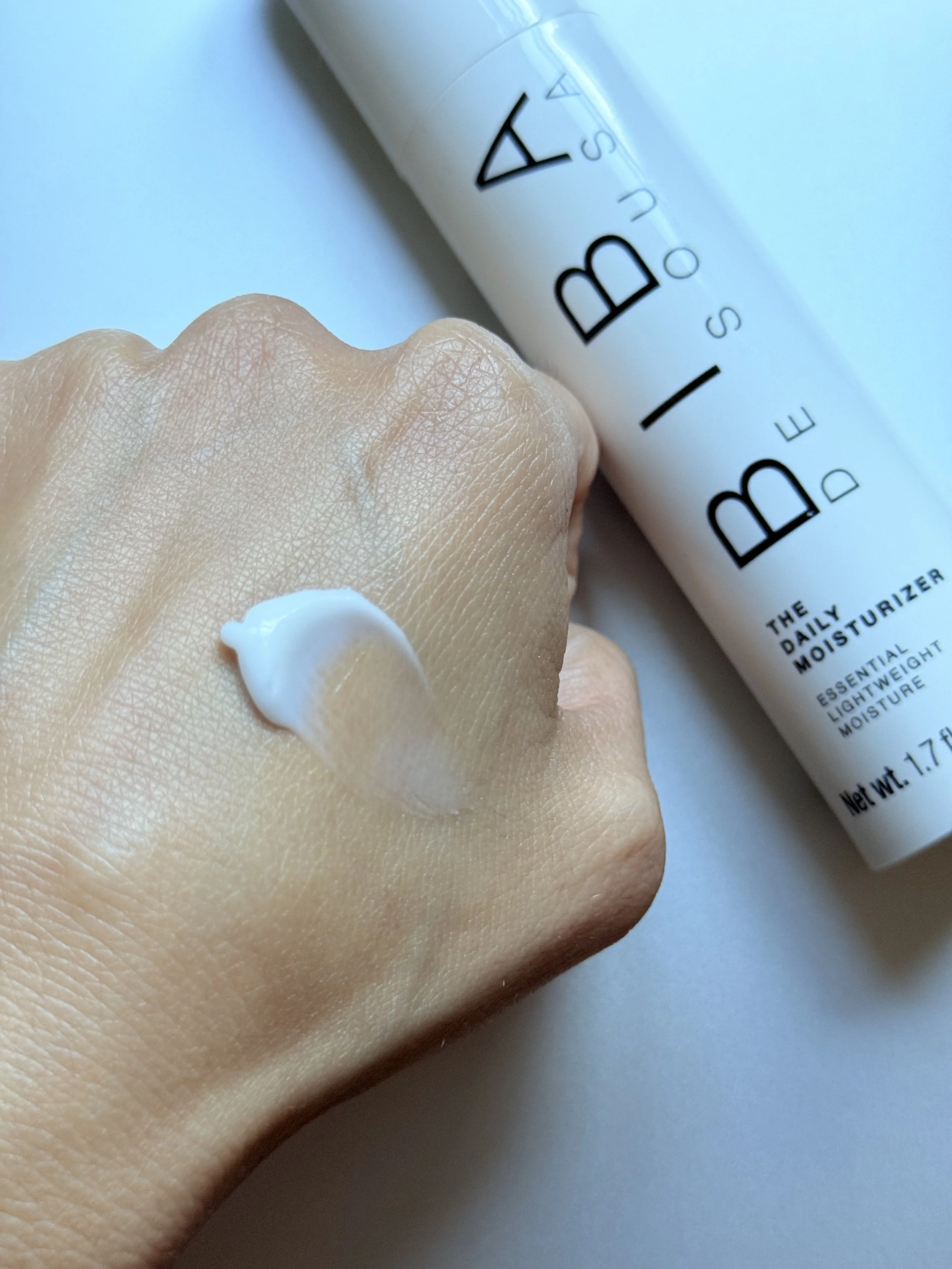 Biba De Sousa The Daily Moisturizer swatch beside white pump bottle