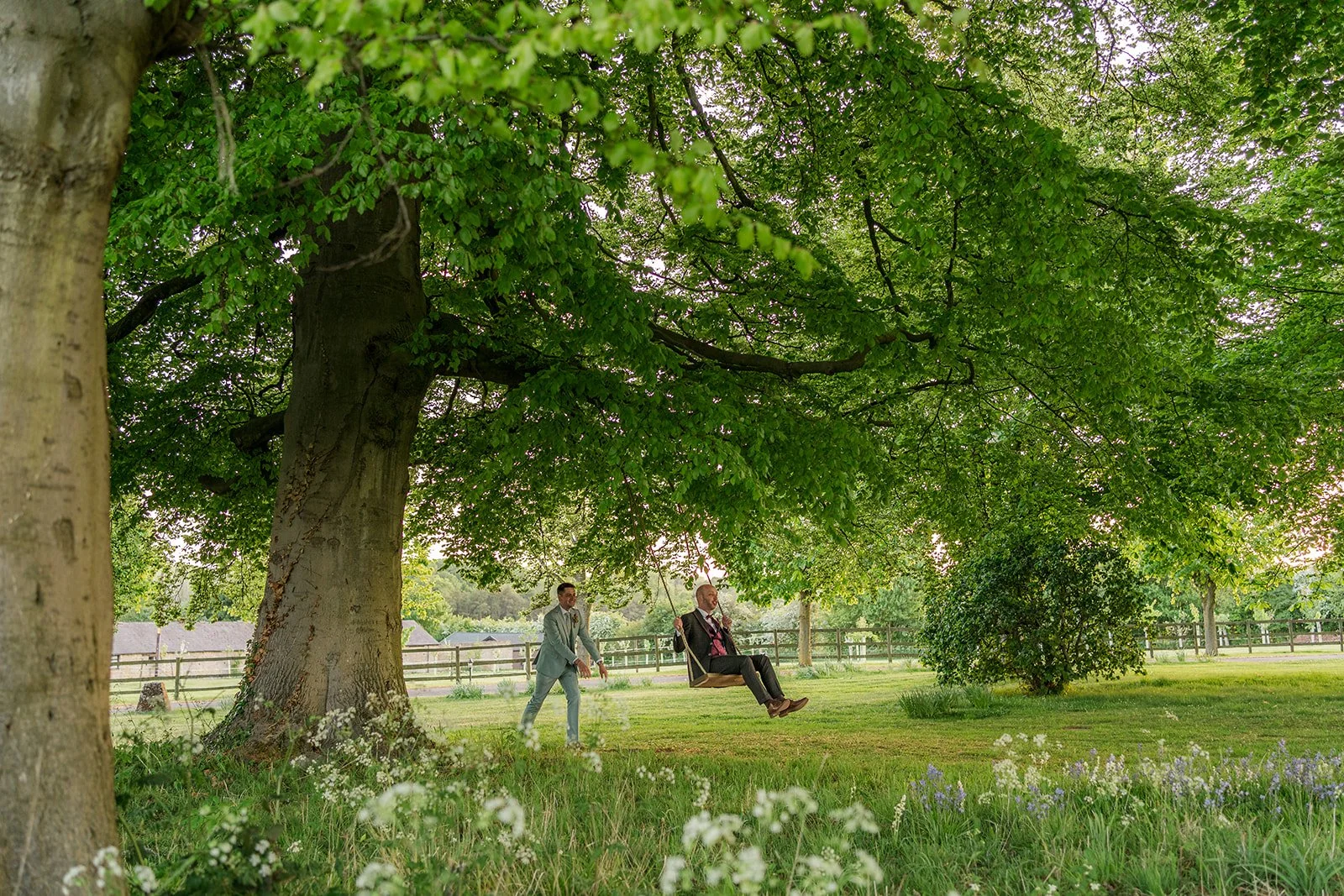 Sam & Gavin enjoying the tree swing at The Great Barn at Aynho in the Cotswolds, photographed by Just James Weddings for playful documentary wedding portraits.