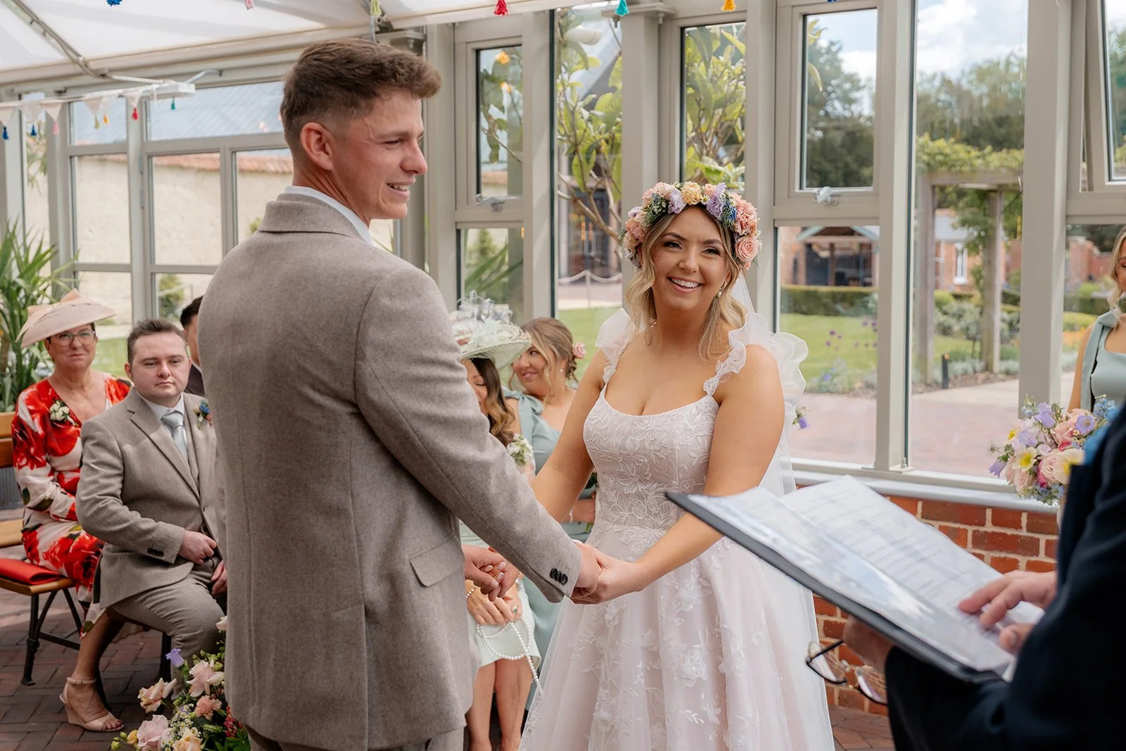 Jaye & Josh holding hands and smiling during their ceremony at Syrencot in Wiltshire, photographed by Just James Weddings for joyful natural wedding ceremony moments.