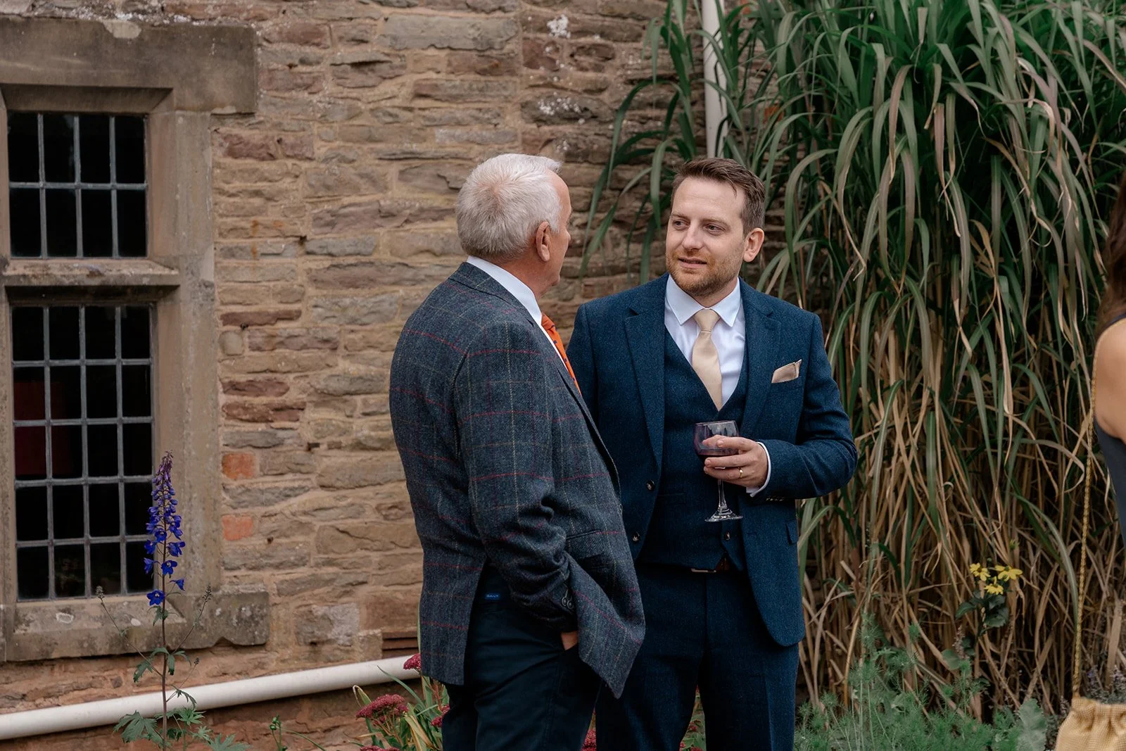 Lloyd chatting with a wedding guest outside Broadfield Court in Herefordshire, photographed by Just James Weddings for relaxed candid reception photography.