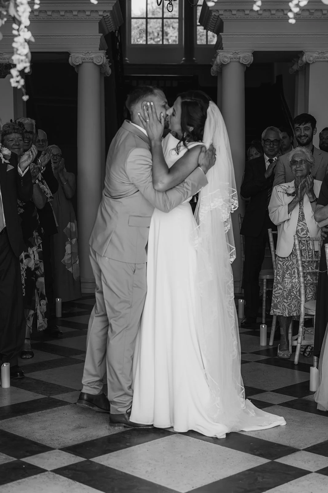 lack and white photo of Michelle & Andy sharing their first kiss during their ceremony at Crowcombe Court in the UK, photographed by Just James Weddings.