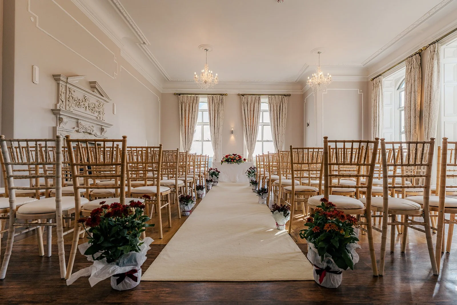 Indoor ceremony room at Eastwood Park in Gloucestershire, with gold chairs, aisle flowers and soft natural light, photographed by Just James Weddings for wedding venue inspiration.