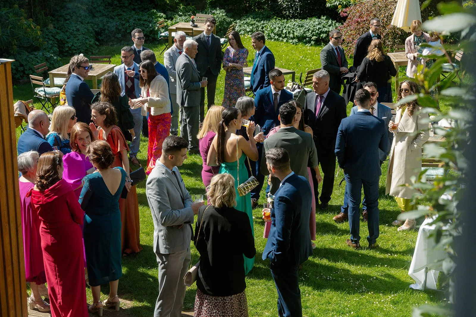 Guests mingle in the sunny garden during Ruth and Carmelo’s wedding reception at No. 4 Clifton Village in Bristol, UK, creating a relaxed outdoor celebration.