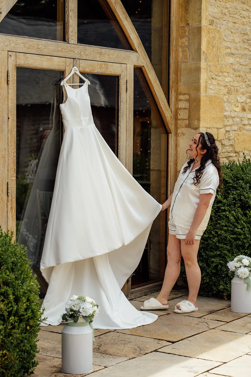 Chloe admires her wedding dress outside the rustic stone barn before marrying Armani at The Barn at Upcote in Gloucestershire, photographed by Just James Weddings.