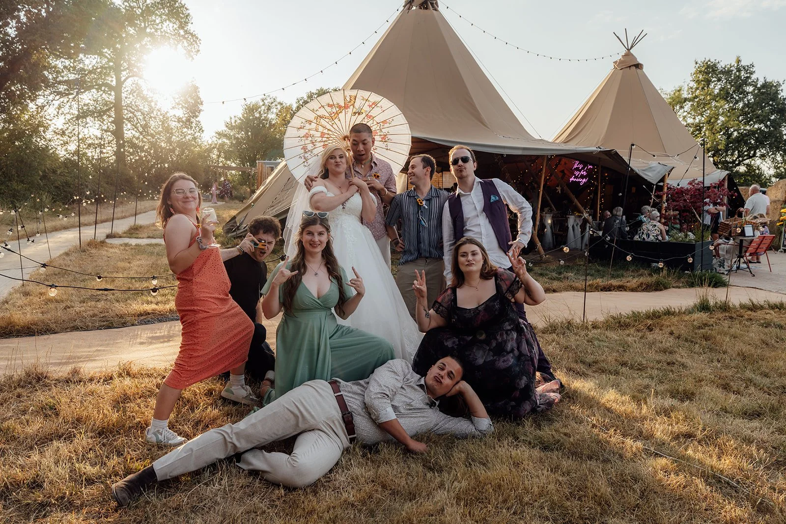 Lucy laughing with friends during a fun group portrait outside the tipi reception at Curated Canvas at Noah’s Pond in Somerset, photographed by Just James Weddings.