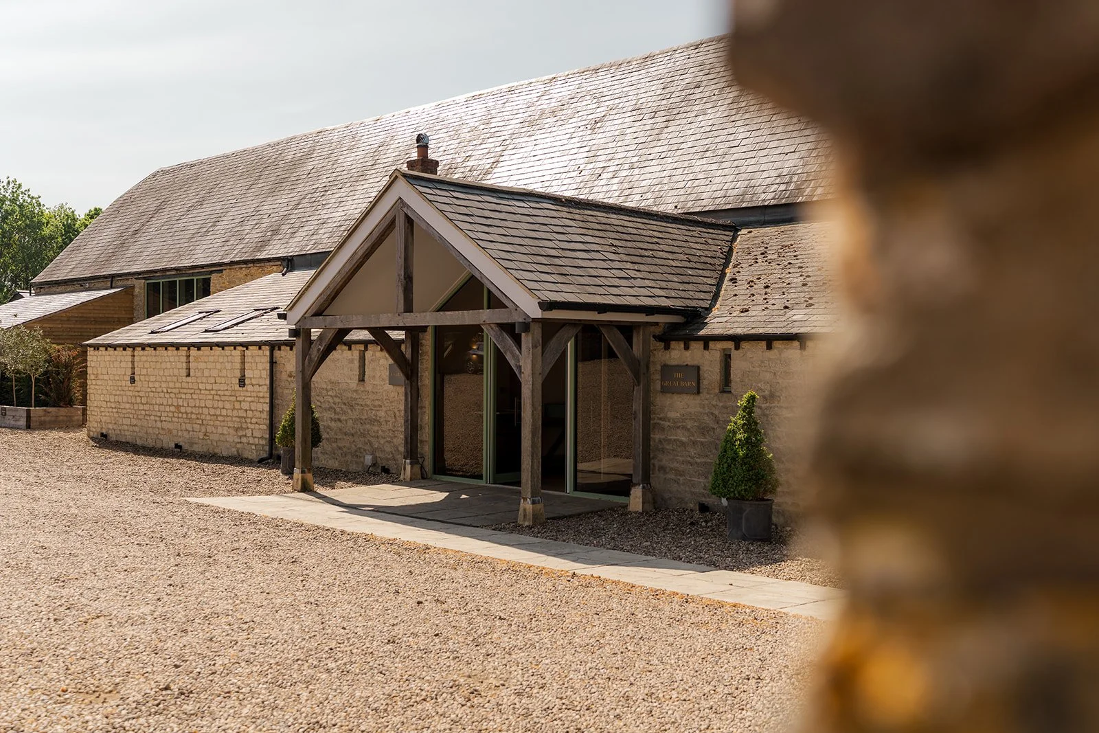 Exterior view of The Great Barn at Aynho in the Cotswolds, showing the stone barn entrance and gravel courtyard, photographed by Just James Weddings for wedding venue inspiration.