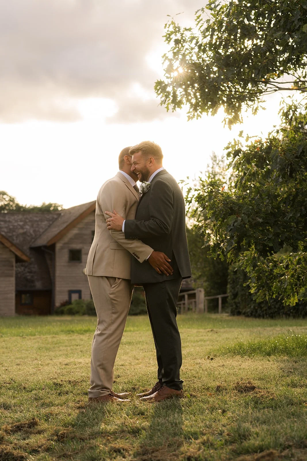 Aaron & Jack share a quiet embrace during golden-hour portraits beneath a tree outside Rock Village Hall in Worcestershire, photographed by Just James Weddings.