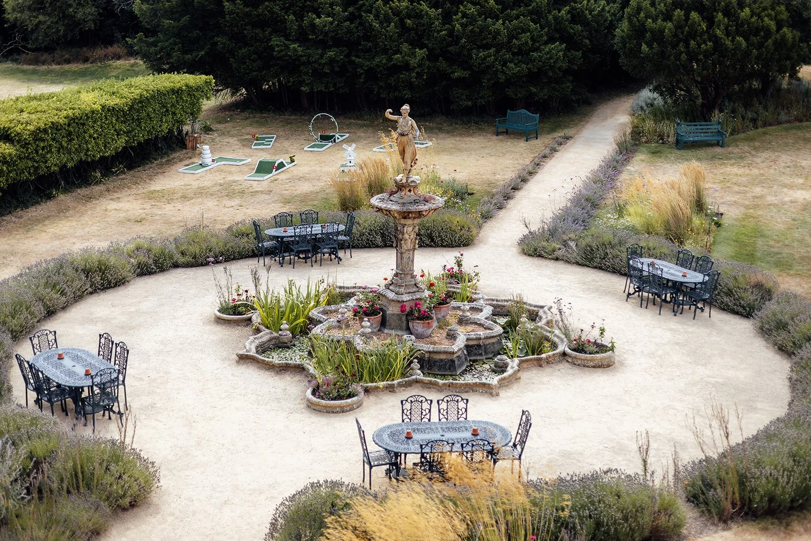 Formal garden at Clevedon Hall in Somerset, with a central fountain, outdoor tables, pathways and landscaped planting, photographed by Just James Weddings.