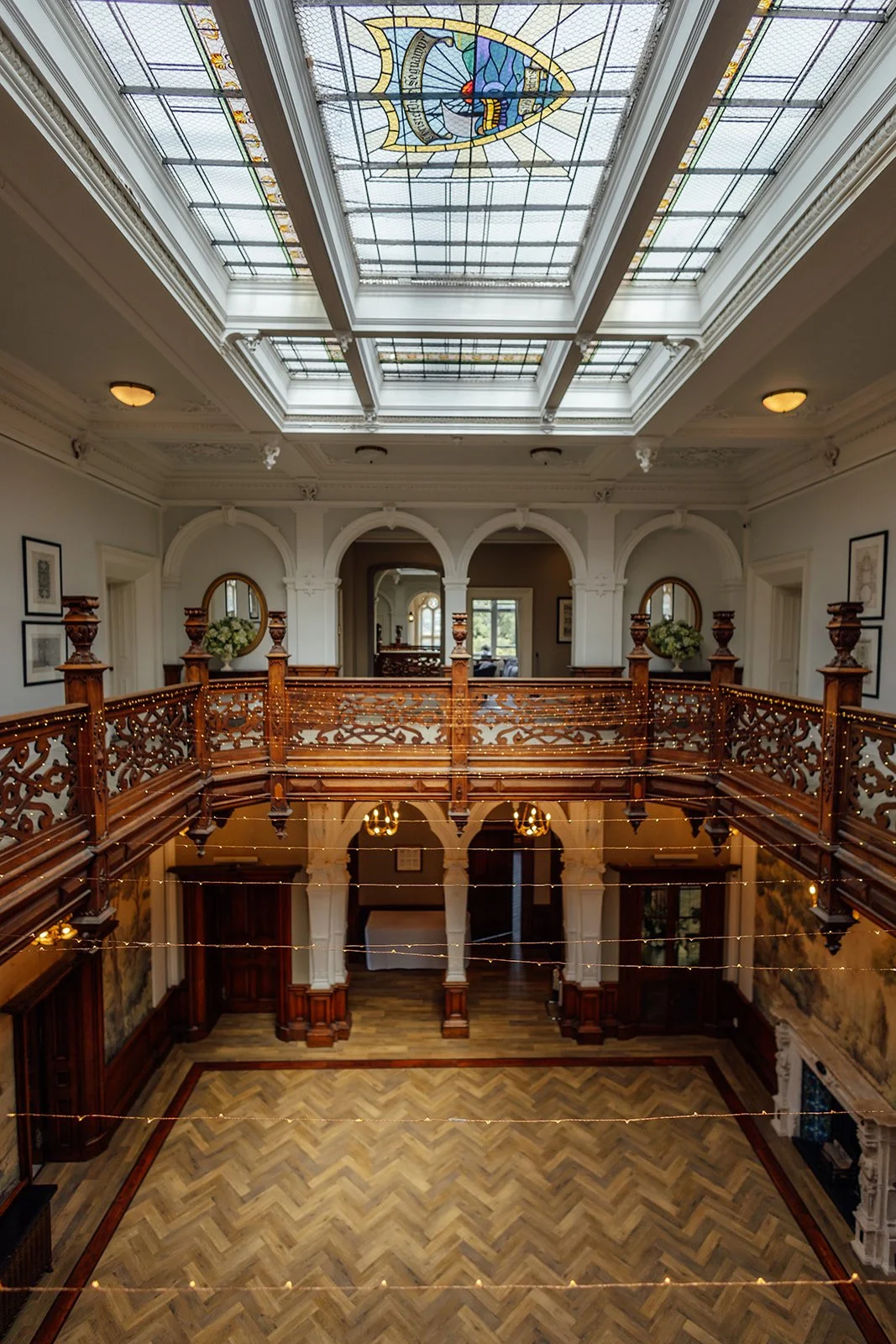 Interior balcony and entrance hall at Clevedon Hall in Somerset, with carved wooden railings, period details and a glass ceiling, photographed by Just James Weddings.