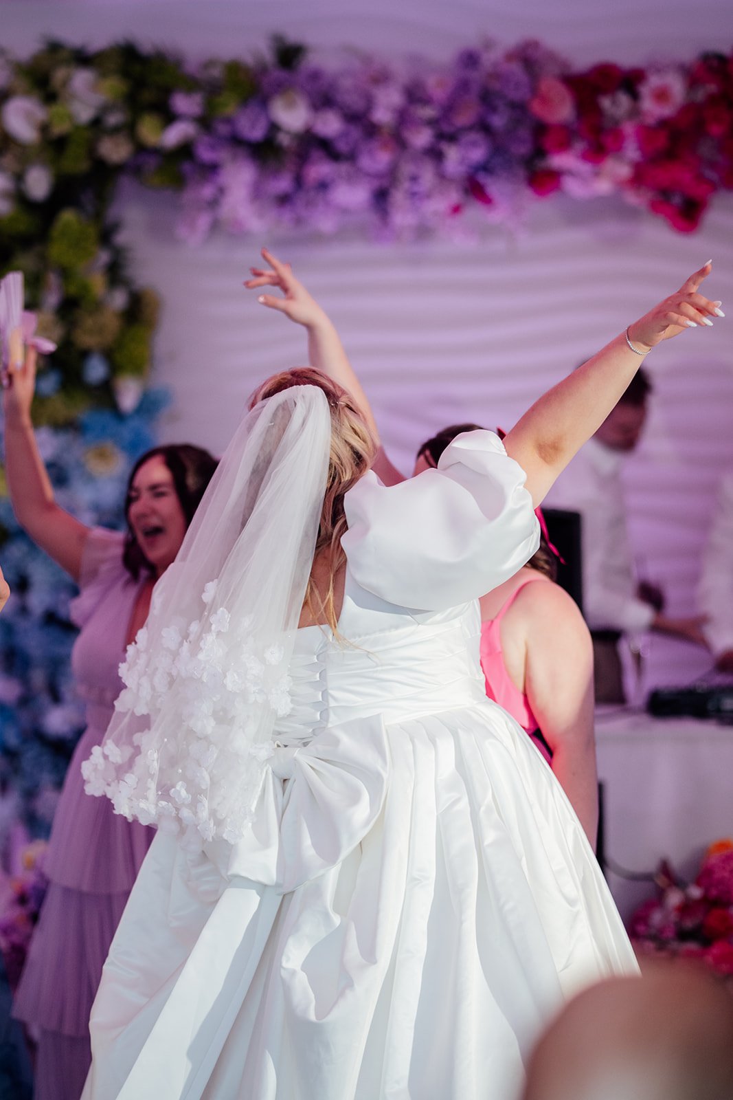Holly dances with her arms raised as bridesmaids celebrate around her during the evening reception at Sandy Cove Hotel in North Devon, photographed by Just James Weddings.