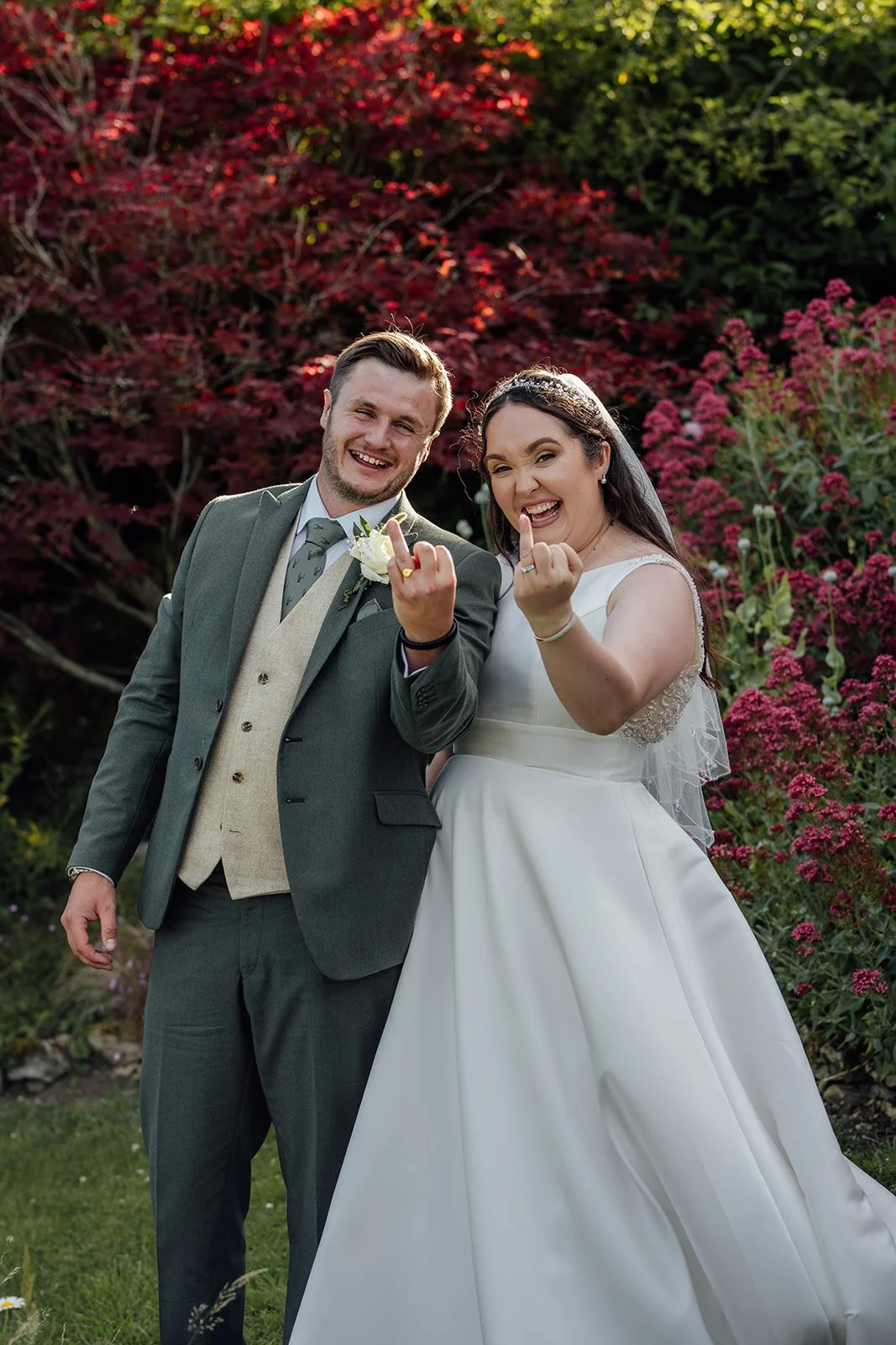 Chloe & Armani smiling together in the gardens at The Barn at Upcote in the Cotswolds, photographed by Just James Weddings for fun relaxed wedding portraits.