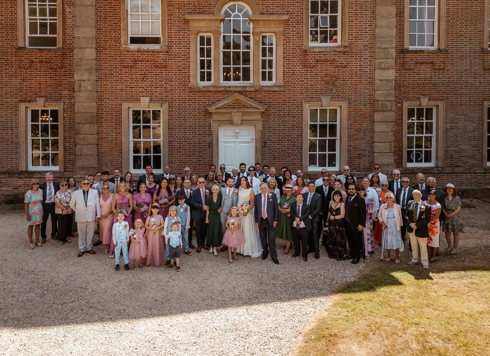 Michelle and Andy pose with their wedding guests in front of Crowcombe Court in Somerset, UK, for a large group photo outside the historic country house.
