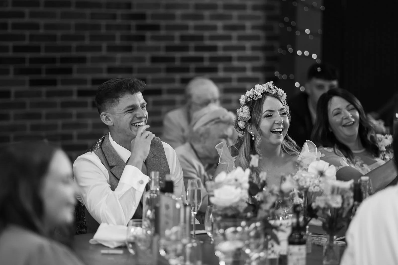 Black and white photo of Jaye & Josh laughing during their wedding breakfast at Syrencot in Wiltshire, photographed by Just James Weddings for candid reception moments.