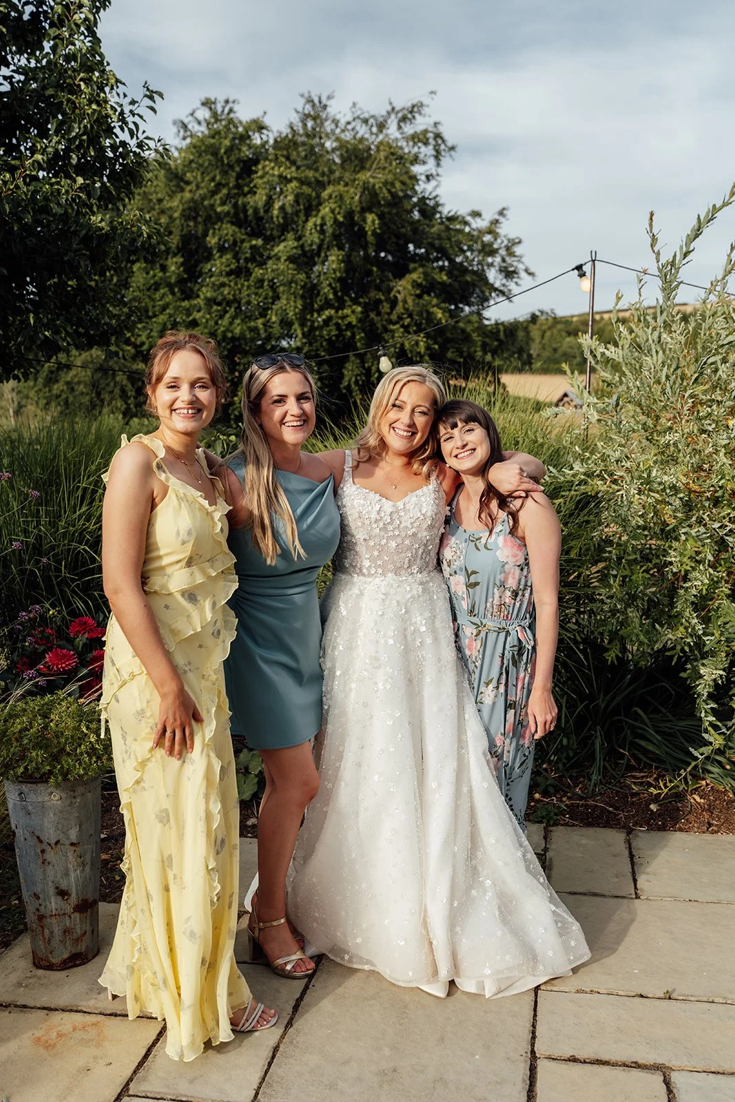 Elise smiling with friends during relaxed wedding guest portraits in the gardens at Bowerchalke Barn in Wiltshire, photographed by Just James Weddings.
