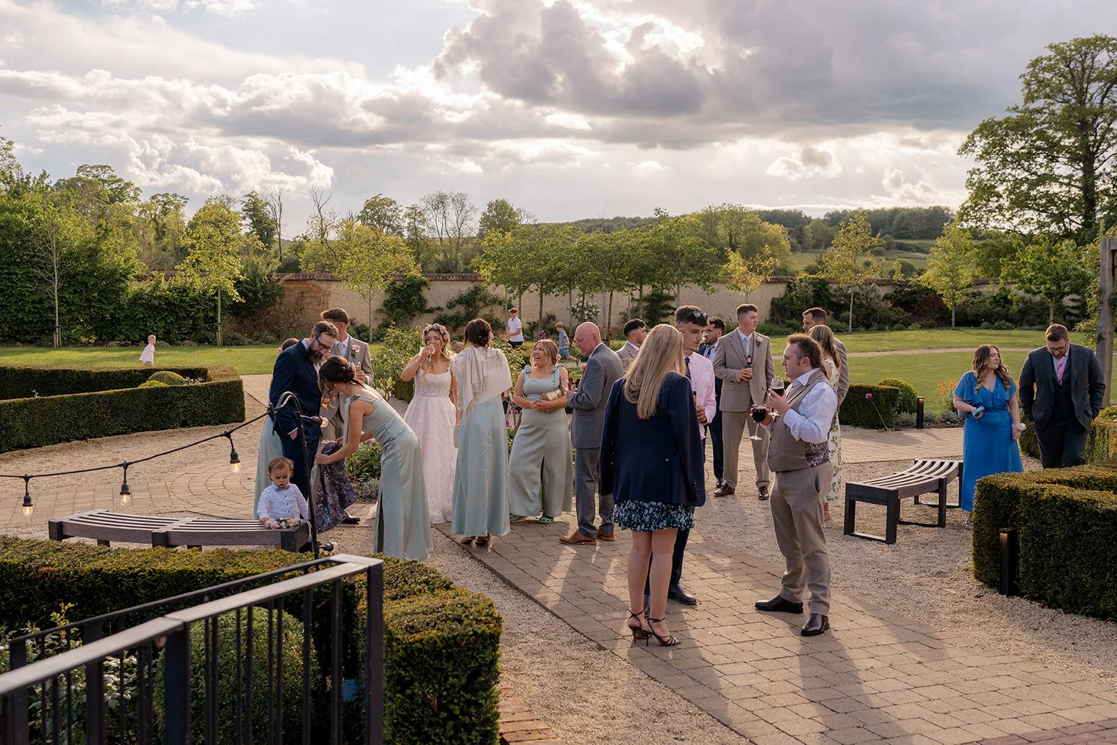 Guests enjoying the outdoor drinks reception in the gardens at Syrencot in Wiltshire, photographed by Just James Weddings for candid wedding day moments.