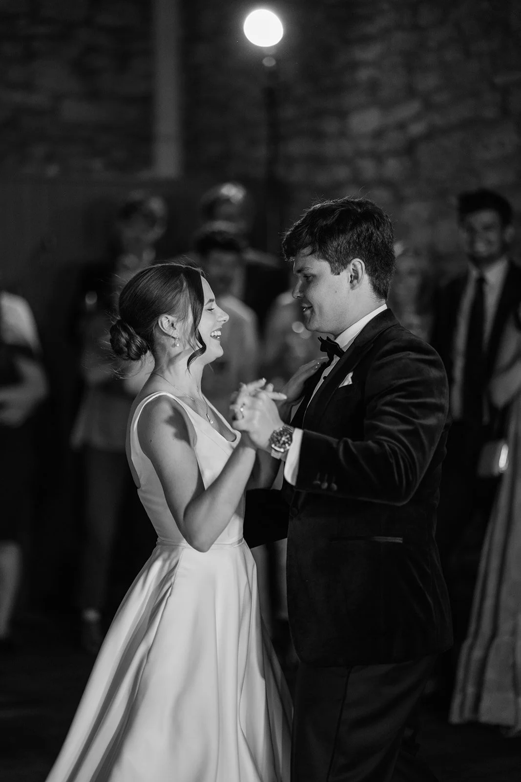 Black and white photo of Rachel & Tom smiling together during their first dance at Brympton House in Somerset, photographed by Just James Weddings.