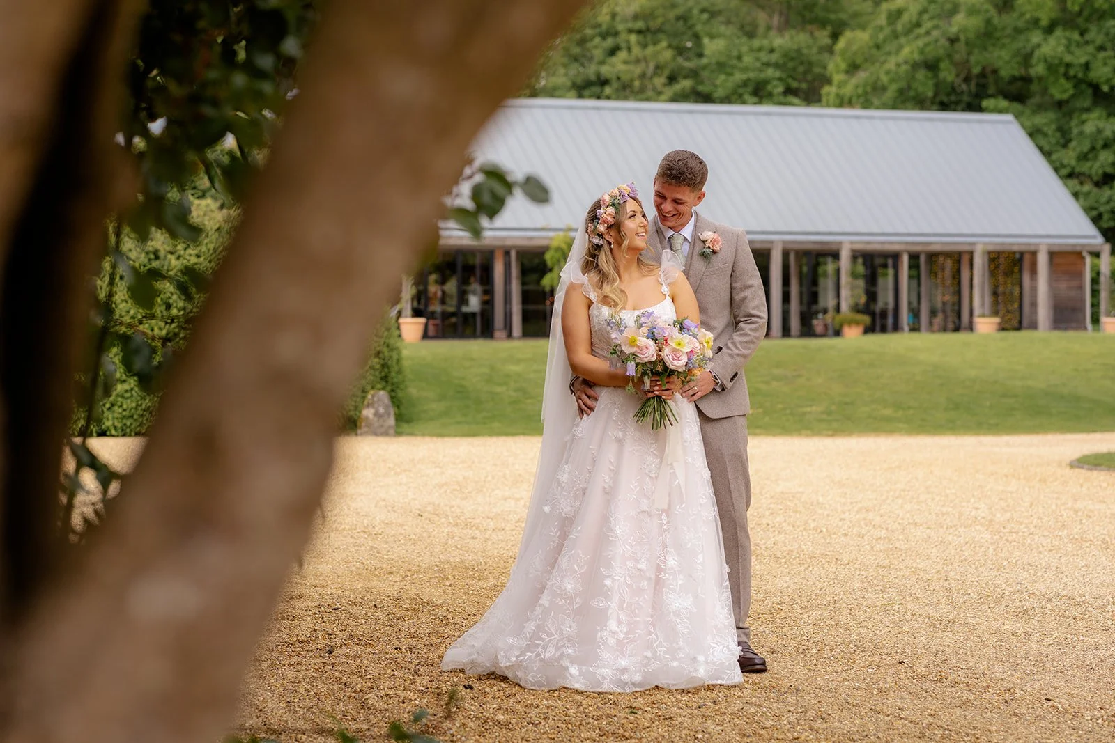 Jaye and Josh smiling together during relaxed wedding portraits outside Syrencot in Wiltshire, photographed by Just James Weddings.