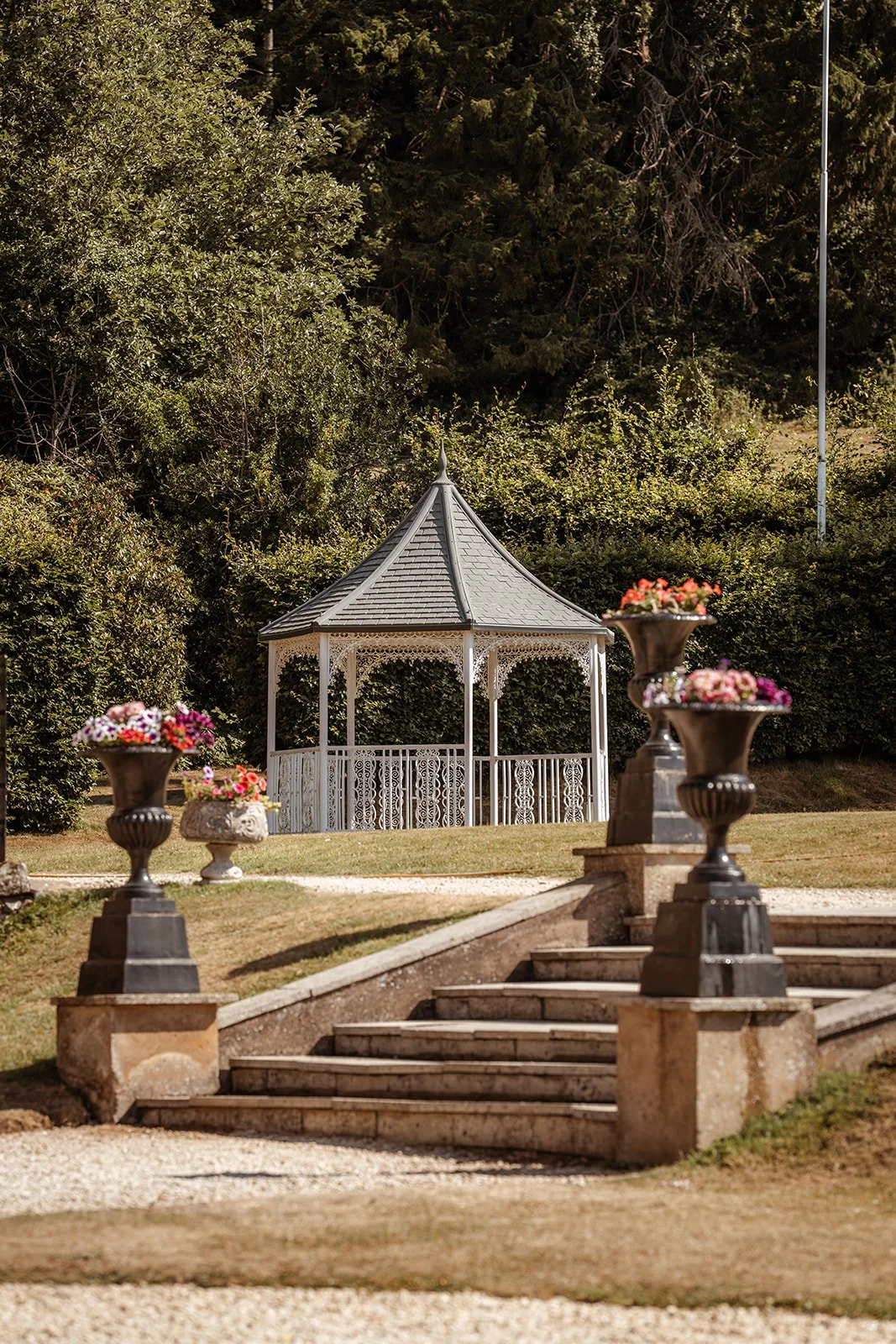 Garden gazebo and stone steps at Crowcombe Court in Somerset, UK, decorated with colourful flowers during Michelle and Andy’s summer wedding celebration.