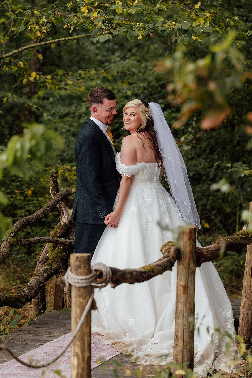 Lucy and Matthew sharing a relaxed woodland wedding portrait surrounded by greenery at Curated Canvas at Noah’s Pond in Somerset, photographed by Just James Weddings.