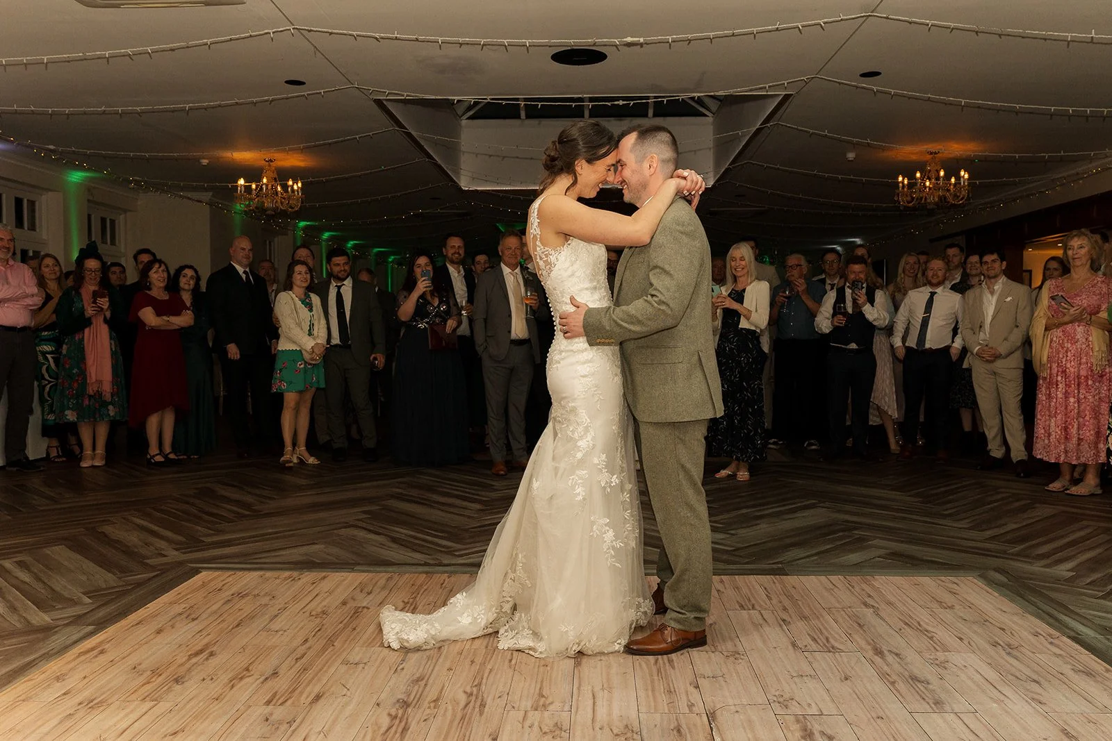 Anna and Chris share their first dance at Elmhay Park in Somerset, UK, holding each other closely on the dance floor as guests watch around them. A romantic evening reception portrait from Anna & Chris’s wedding day, full of warmth and joy.