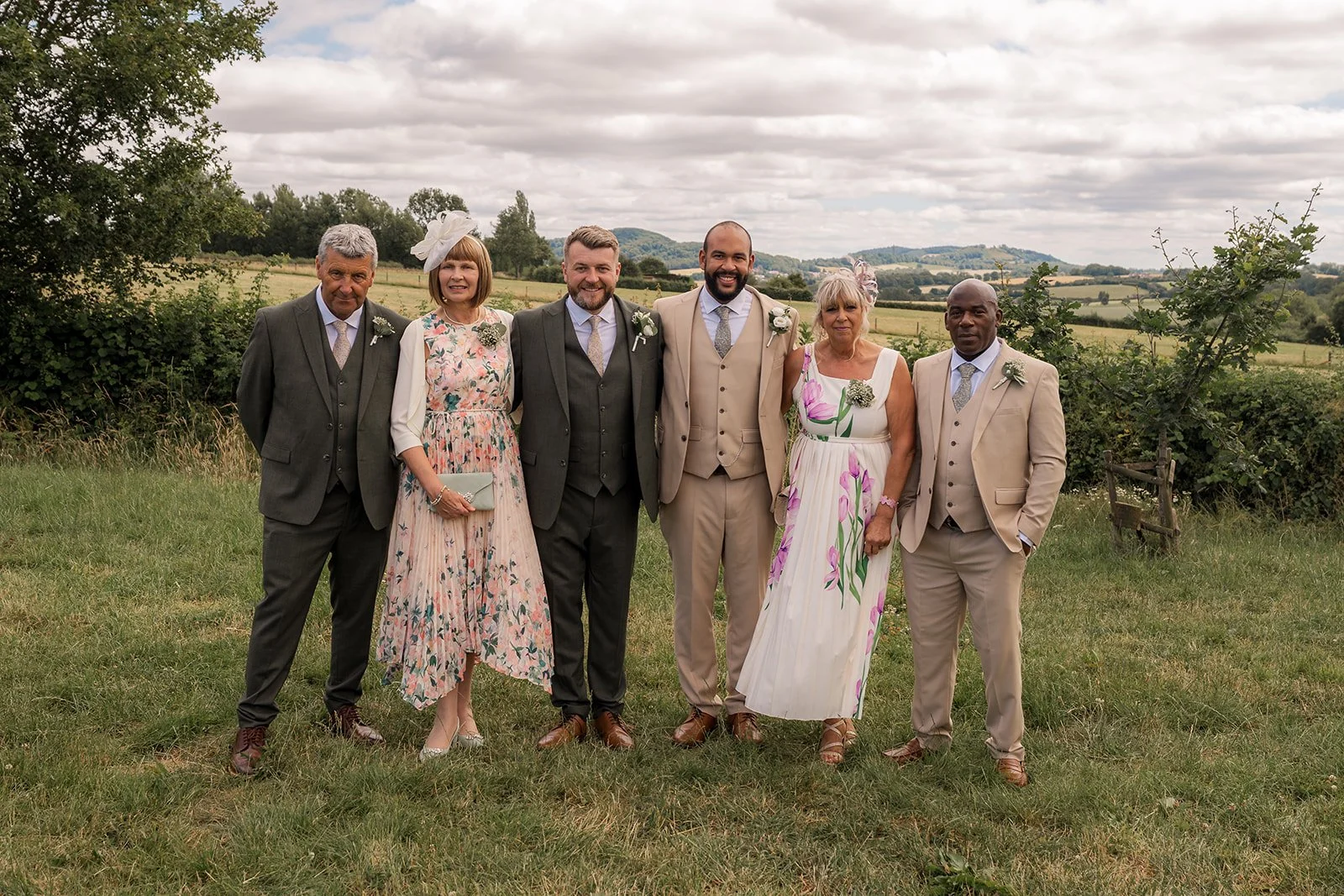 Aaron & Jack pose with their parents against the Worcestershire countryside following their wedding ceremony at Rock Village Hall, photographed by Just James Weddings.