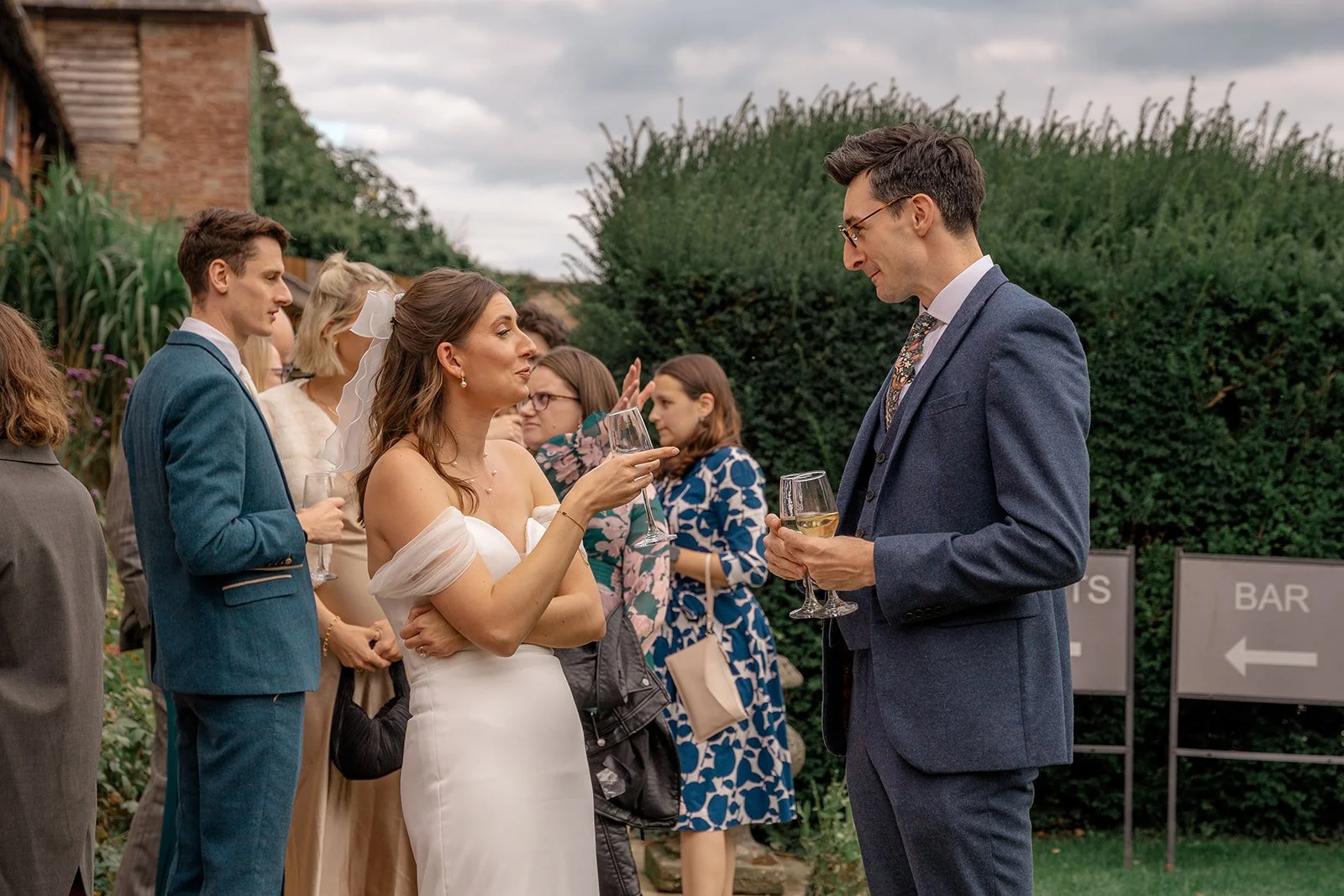 Lilly chatting with a wedding guest during the drinks reception at Broadfield Court in Herefordshire, photographed by Just James Weddings for candid documentary wedding moments.