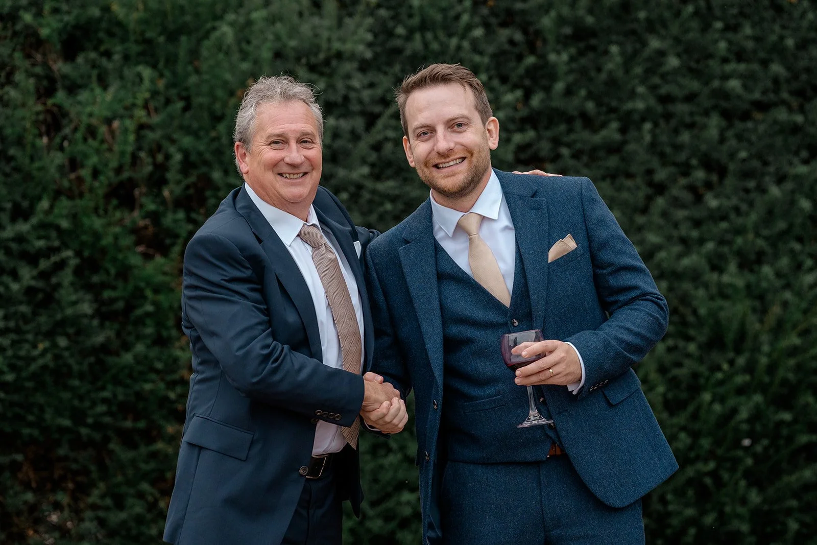 Lloyd smiling with a wedding guest during the drinks reception at Broadfield Court in Herefordshire, photographed by Just James Weddings for natural documentary wedding photography.
