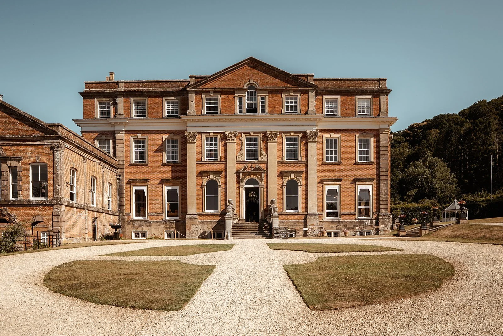 Exterior view of Crowcombe Court in the UK, showing the historic red brick manor house, gravel driveway and front lawns, photographed by Just James Weddings for wedding venue inspiration.