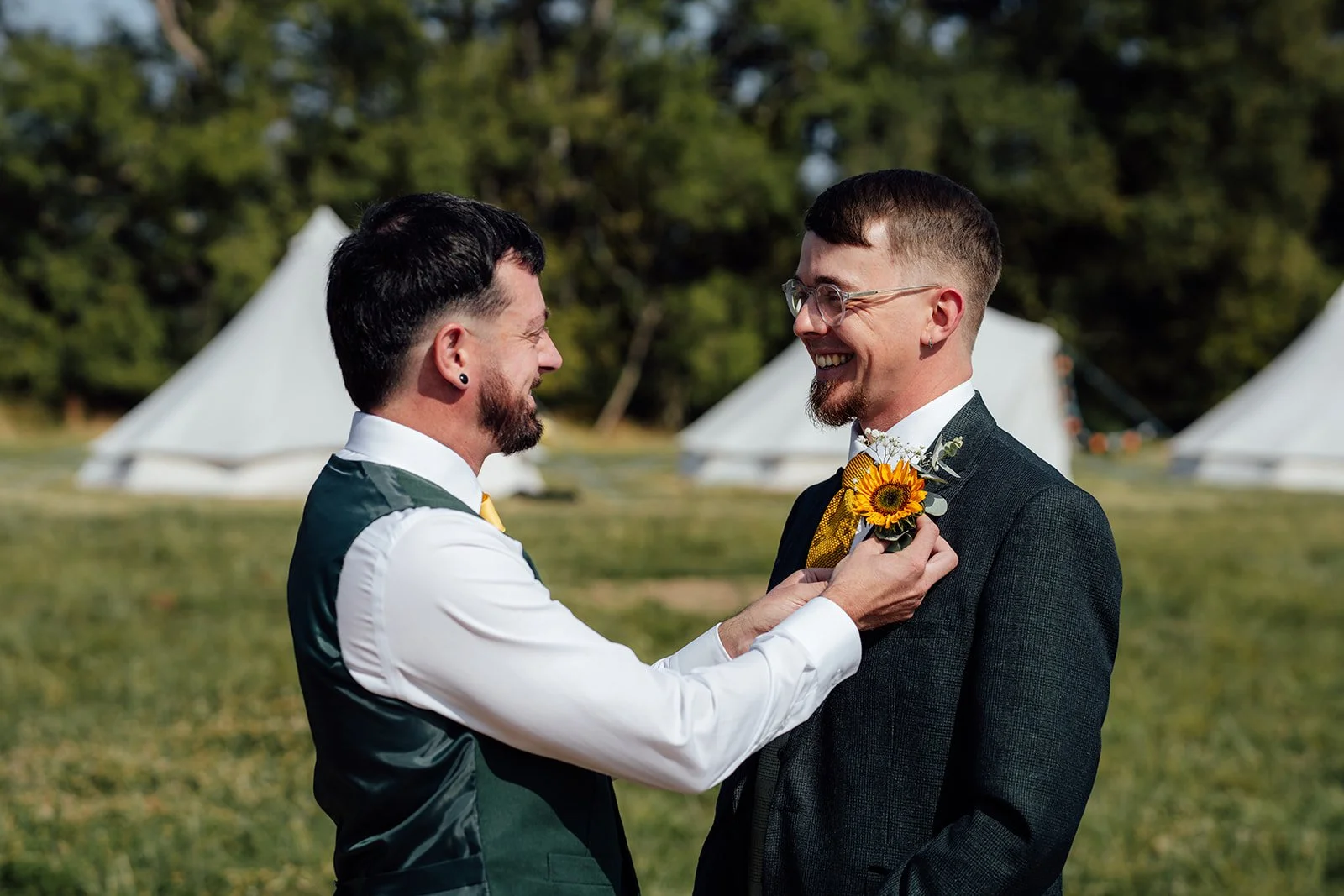 Lucy adjusting Matthew’s sunflower buttonhole before their outdoor wedding at Curated Canvas at Noah’s Pond in Somerset, photographed by Just James Weddings.