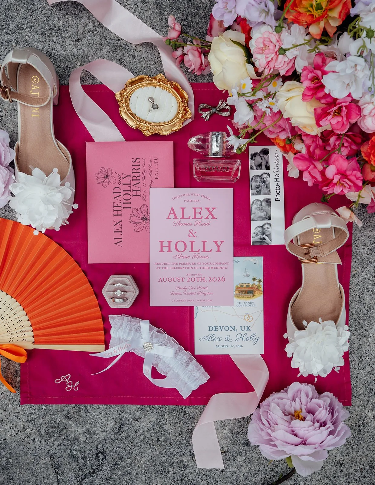 Flat lay of Holly & Alex’s colourful wedding details, including invitations, rings, shoes, perfume, flowers and keepsakes at Sandy Cove Hotel in North Devon, photographed by Just James Weddings.