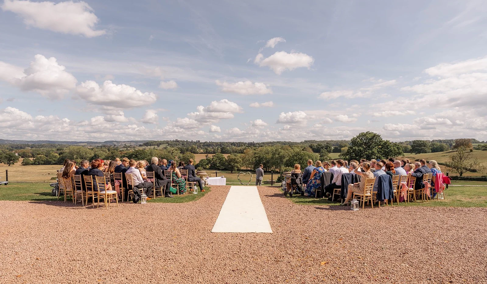 Outdoor ceremony at Eastwood Park in Gloucestershire, with guests seated on the lawn and countryside views behind, photographed by Just James Weddings for wedding ceremony inspiration.