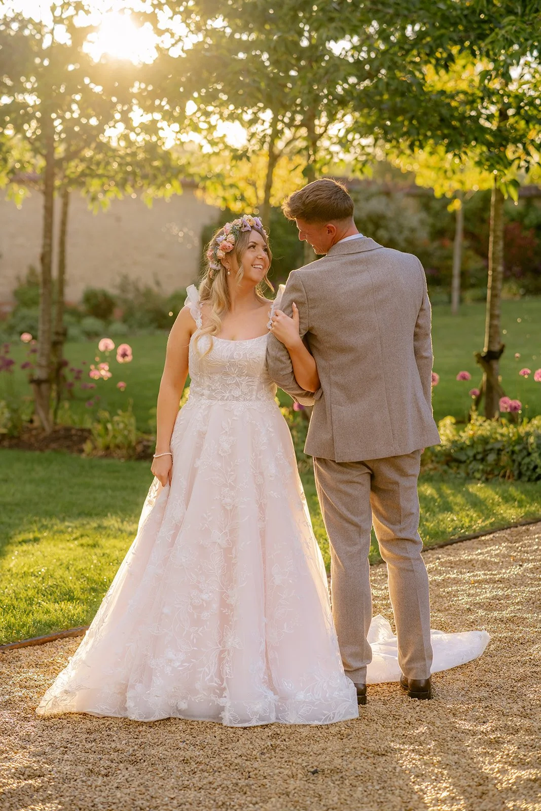 Jaye & Josh walking together through the gardens at Syrencot in Wiltshire, photographed by Just James Weddings in warm evening light for natural wedding portraits.